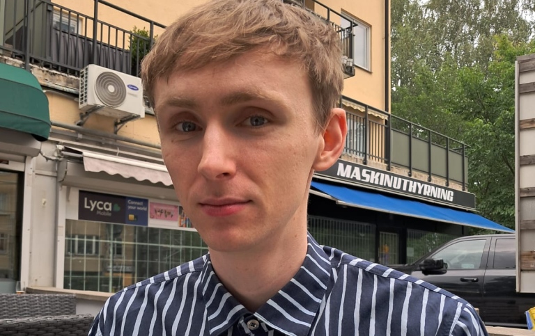 Man med ljust kortklippt hår och blåvitrandig skjorta
